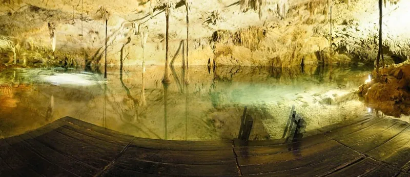 Crystal-clear water reflecting stalactites in Cenote Taak Bi Ha